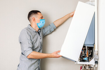 Wall Mural - Plumber attaches Trying To Fix the Problem with the Residential Heating Equipment. Repair of a gas boiler