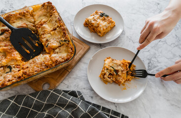 woman eating lasagna with basil and tomatoes