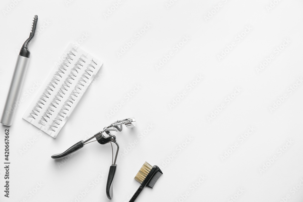 Set of false eyelashes and tools on light background
