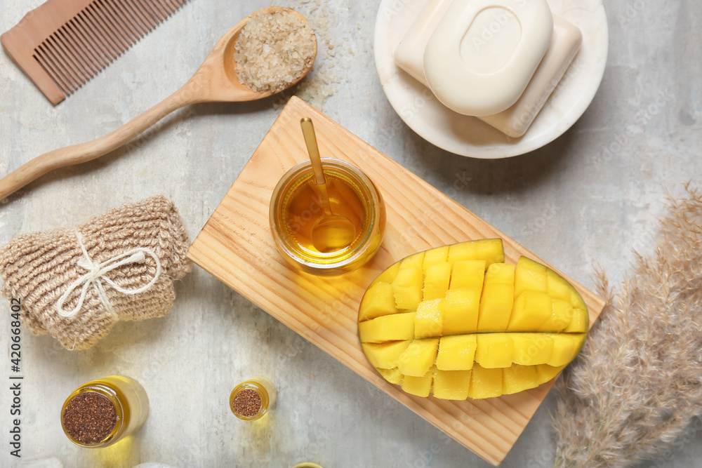 Composition with mango essential oil and bath supplies on grunge background