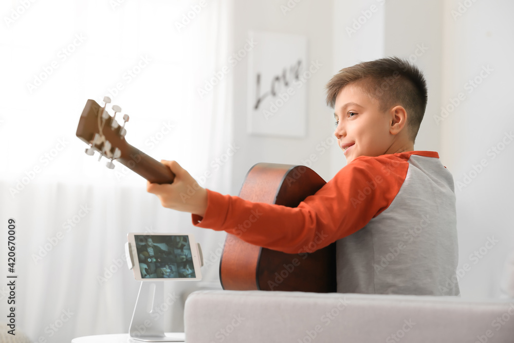 Little boy taking music lessons online at home