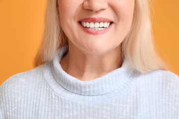 Canvas Print - Happy mature woman with beautiful smile on color background, closeup