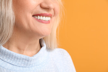 Canvas Print - Happy mature woman with beautiful smile on color background, closeup