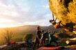 © Manu Prats/Stocksy - Man climbing granite boulder rock near friends