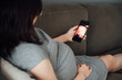 © MaaHoo Studio/Stocksy - Pregnant woman looking at cell phone