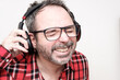 © Jorge Elizaquibel - Portrait of a laughing mature man with bear wearing red plaid shirt and glasses. Wearing headphones.