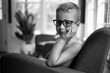 © Jakob Lagerstedt/Stocksy - Handsome young boy with eyeglasses and no shirt sitting in a chair