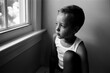 © Jakob Lagerstedt/Stocksy - A handsome young boy in a tank top looking out a window