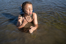 Boy With Muddy Face Lays In Water