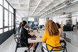 © Sergio Marcos/Stocksy - Group of multiracial businesspeople sitting around table having a remote video conference in modern workplace