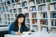 © zheng long/Stocksy - Young woman reading in the library