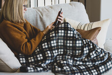 Woman Looking At Her Phone While Relaxing On Couch