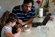 © Eloisa Ramos/Stocksy - father and daughteher having breakfast with laptop on table at typical Andalusian house