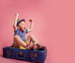 angry upset little kid sitting on the suitcase having upset facial expression wants to travel. child