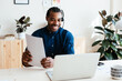 © BONNINSTUDIO/Stocksy - Happy black employee with papers making online call