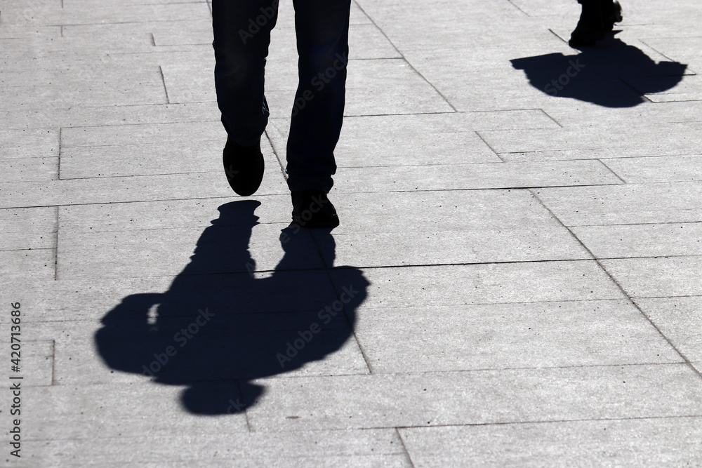 People walking down the street, black silhouette and shadow of man in ...