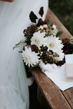 Romantic Flower Bouquet With White And Red Details Next To Wedding Vows And Rings