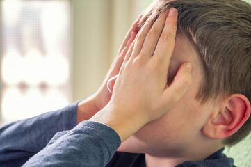 Poster - Trauriges junges Kind sitzt zu Hause im Flur mit Händen vor dem Gesicht