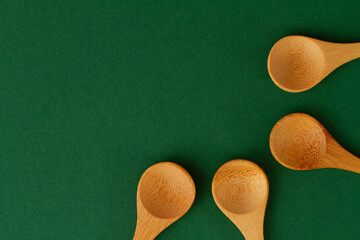 four bamboo spoons placed on a green background