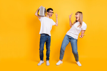 Sticker - Photo of cute two persons dressed white t-shirt glasses showing v-signs listening boom box isolated yellow color background