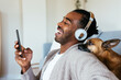 © BONNINSTUDIO/Stocksy - Excited African American guy with smartphone laughing at joke near dog
