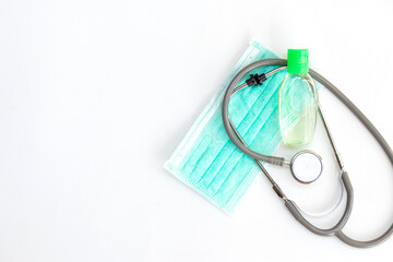 Stethoscope, alcohol gel and green medical mouth mask, face mask protection against pollution, virus, flu. Health care and medical concept on white background.