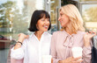 Two mature women having fun while doing shopping and drinking coffee