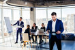 © Дмитрий Ткачук - Successful handsome male mentor, director, businessman in a suit at the office. Working day concept. Team meeting with the boss in the foreground
