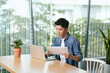 © makistock - Handsome young asian man working at a coffee shop with a laptop and tablet.