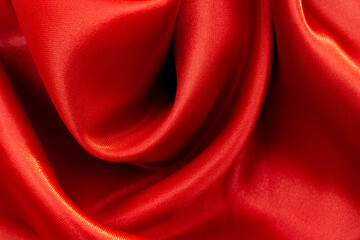 Smooth elegant red silk satin, with random pleats. Close-up, selective focus, abstract background