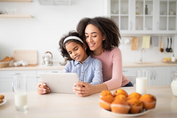 Wall Mural - Black woman and girl using tablet in kitchen