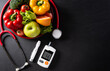 © Siam - Top view of healthy food in plate with stethoscope and diabetes control on dark background. World health day and medical concept.