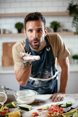 Wall Mural - Young man preparing bread at home. Happy man having fun while baking a fresh pasta