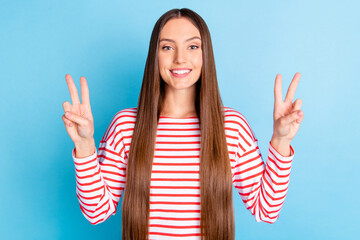 Poster - Photo of sweet shiny young girl wear striped shirt showing two v-signs smiling isolated blue color background