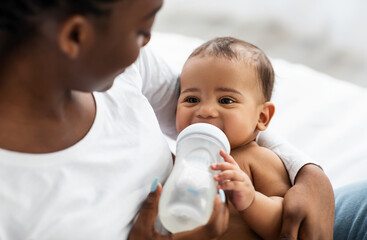 African American woman feeding her child from baby bottle