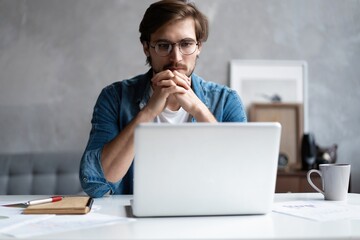 Wall Mural - Thoughtful man looking away while sitting at his working place in office