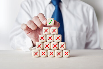 Wall Mural - businessman places the cube with the check mark symbol on top of a wooden cube stack with wrong or c