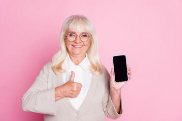 Poster - Photo portrait of woman showing thumb up holding phone with blank space in one hand isolated on pastel pink colored background