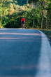 © qunica.com - Fit cyclist rides his bicycle (bike) on an empty road in nature wearing a baseball hat and red t-shirt.