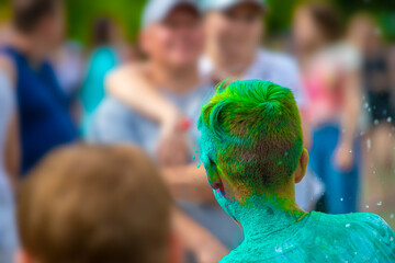 young man sprinkled with multi-colored powder at the Festival of colors.