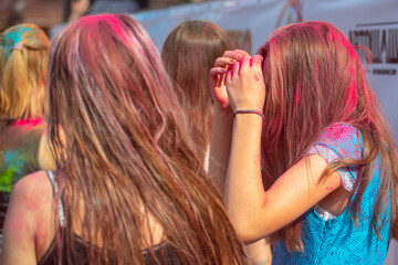 Cheerful girl sprinkled with multi-colored powder at the Festival of colors.