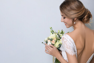 Wall Mural - Young bride with beautiful wedding bouquet on light grey background. Space for text