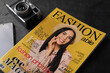 Fashion magazine and camera on black table, closeup
