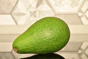 One ripe organic avocado, close-up, on a tile background.