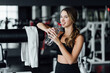 © Тарас Нагирняк - Attractive blonde girl with an athletic body during a workout in the gym drinks water and smiles at the camera