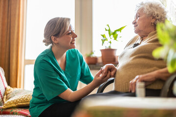 Friendly nurse supporting an elderly lady
