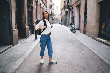 Wall Mural - Beautiful female backpacker visiting ancient town during spring solo vacations looking around in quarter, Caucasian woman dressed in casual clothing recreating during international holidays