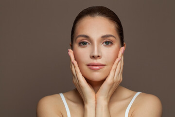 Wall Mural - Cute young woman spa model with clear skin on brown background. Skincare and facial treatment concept