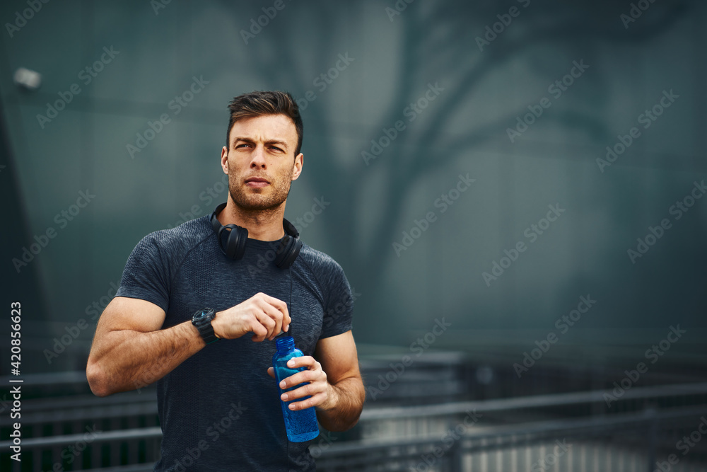 Young handsome men resting after jogging in the city and open a bottle of water - obrazy, fototapety, plakaty 