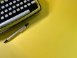 © Józef - On a yellow background there is a typewriter and a wooden pen